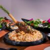 A delicious gourmet lamb shank served with biryani rice and fresh salads on a dining table.